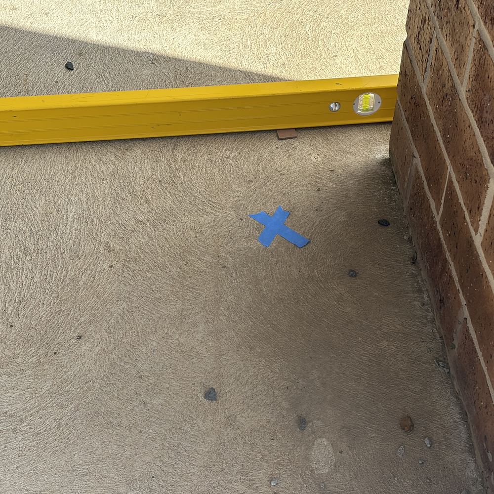 Uneven alfresco concrete holding water around the base of a brick pier, found during a defect investigation in Winter Valley
